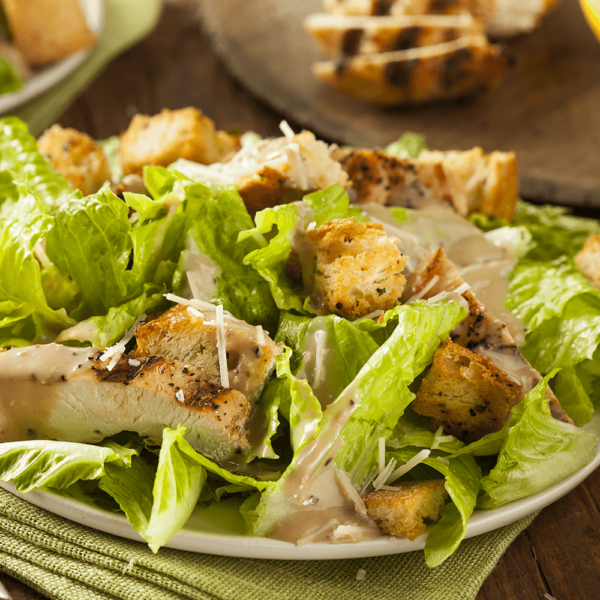 Romaine lettuce with caesar dressing topped with shredded parmesan and croutons